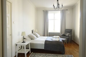 Une chambre à coucher comprenant un lit, une table de chevet, une lampe, une chaise et une vue sur l’extérieur.