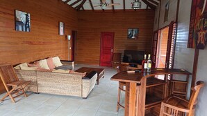 A cozy wooden cabin with a sofa, chairs, a TV, and a bar area.