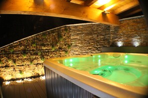 A hot tub with a stone wall backdrop and wooden ceiling beams. - NEW APARTMENT WITH PRIVATE JACUZZI CHEMINEE CLASS 5 STARS (Les Avanchers-Valmorel)