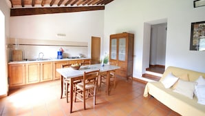 A kitchen with wooden cabinets, a dining table, and a sofa.