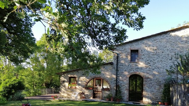 A stone building with a lawn, potted plants, and a lawnmower.