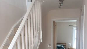 Una escalera que conduce a un dormitorio con cama, mesita de noche y ventana.
