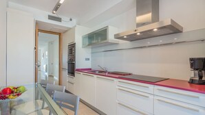 A modern kitchen with white cabinets, a red countertop, and stainless steel appliances. - Apartment Colorado 3B By SunVillas Mallorca (Port de Pollensa)