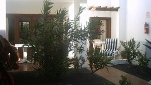 A courtyard with a seating area, a small tree, and a building with a white facade. - 2 Bed Ground Floor in small complex and close to all amenities 1 minute seafront (Puerto del Carmen)