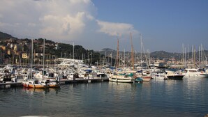 A marina with numerous boats docked, a clear sky, and buildings in the background. - Charming House in an Authentic Italian Mountain Village (Rezzo)