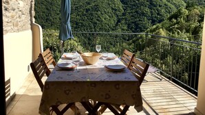 A table set outdoors with a mountain view, a tablecloth, chairs, and a wine glass. - Charming House in an Authentic Italian Mountain Village (Rezzo)