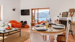 A dining area with a glass table, white chairs, and a view of the sea.