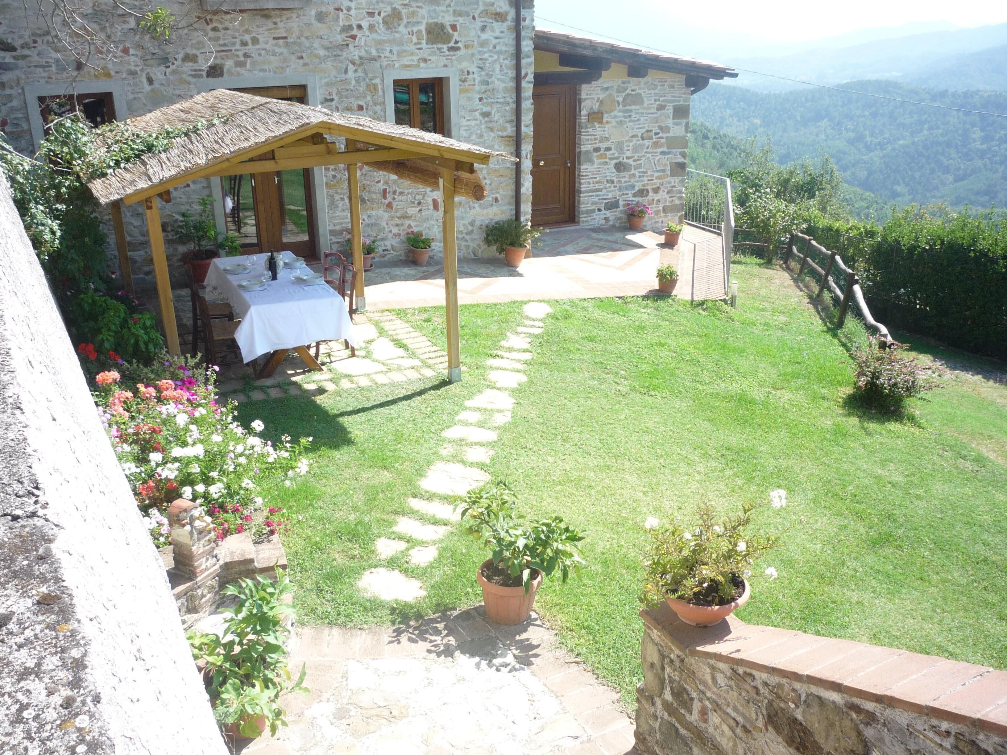 A stone house with a patio, a table set for dining, and potted plants.