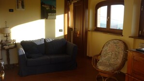 A living room with a sofa, a chair, a lamp, a door, and a window. - Casale Lavinia - country house with swimming pool and magnificent oversight wifi (Lucca)