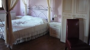 A bedroom with a four-poster bed, a nightstand with a lamp, a chair, and a wardrobe. - Casale Lavinia - country house with swimming pool and magnificent oversight wifi (Lucca)