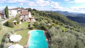 A stone house with a swimming pool surrounded by lush greenery and mountains in the background. - Casale Lavinia - country house with swimming pool and magnificent oversight wifi (Lucca)