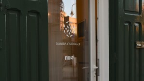 Une porte verte avec un cadre blanc et un vitrage, sur laquelle on peut lire l’inscription « DIMORA CARDINALE » ainsi que des icônes de réseaux sociaux.