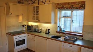 A kitchen with white cabinets, a built-in oven, a sink, and a window with a floral valance. - Private, spacious, elegant flat with lovely views, in a beautiful area (Westcott)