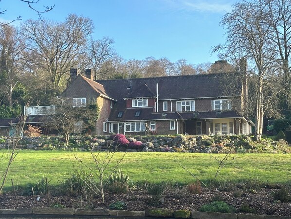 A large, two-story house with a sloped roof, multiple windows, and a well-maintained garden in front. - Private, spacious, elegant flat with lovely views, in a beautiful area (Westcott)