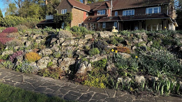 A large house with a stone pathway leading to the entrance, surrounded by a garden with various plants and flowers. - Private, spacious, elegant flat with lovely views, in a beautiful area (Westcott)