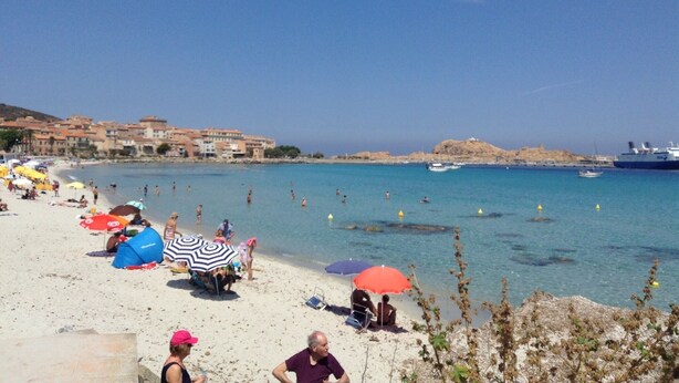Ein Strand mit Personen, Sonnenschirmen und Booten.