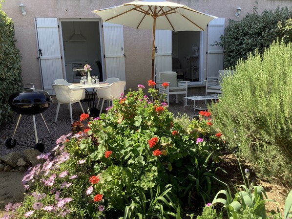 Un patio al aire libre con una parrilla, una mesa de comedor, sillas y una sombrilla.