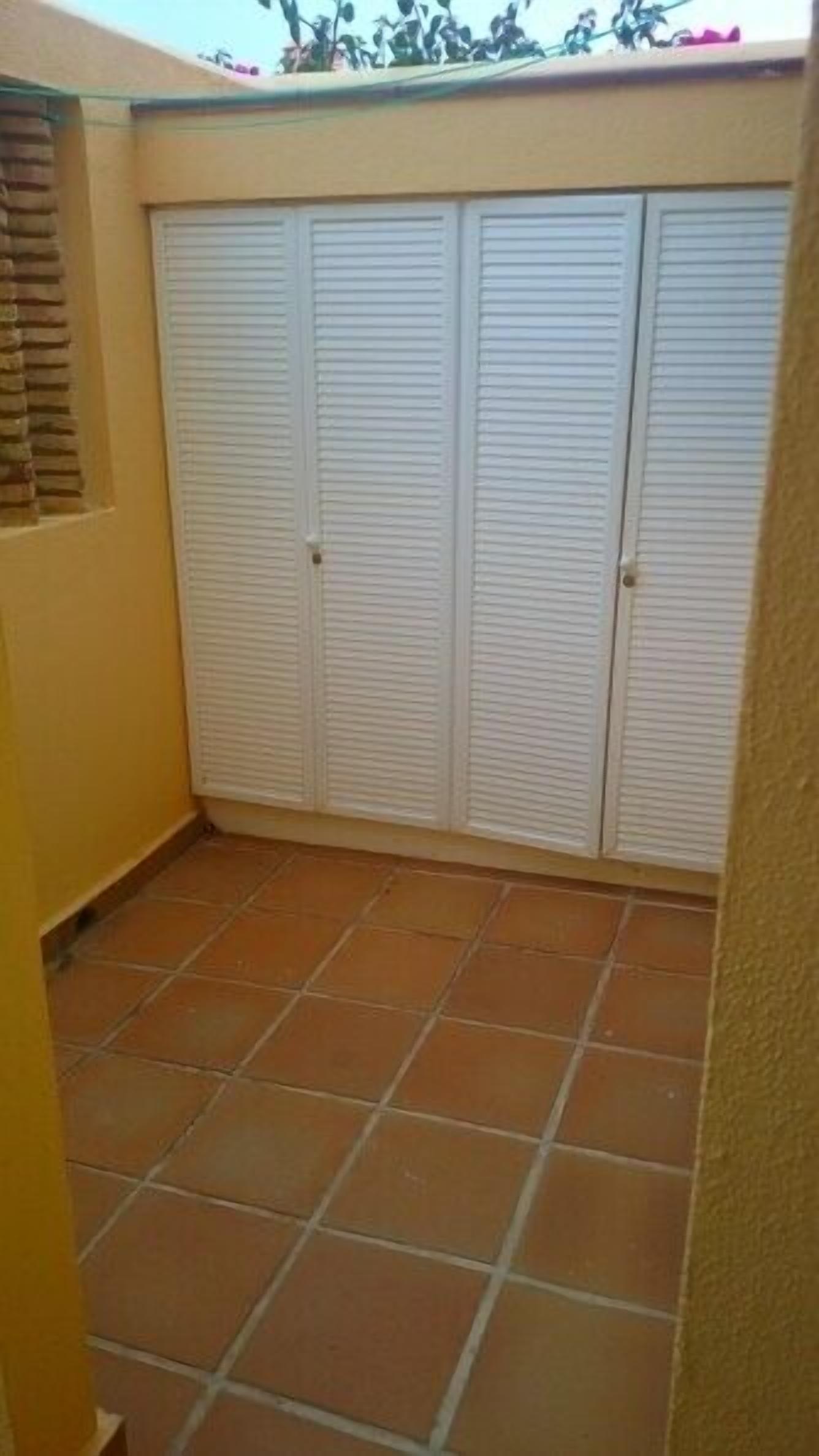 A small enclosed patio area with a tiled floor and a set of white louvered doors.