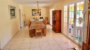 Un coin repas avec une table dressée pour quatre personnes, des chaises en bois, un lustre et un buffet aux portes vitrées.