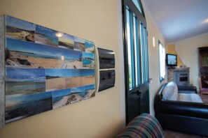A wall with a series of photographs depicting coastal scenes, a sofa, and a television in a living room. - Country holiday home - AGLIENTUHouse with garden (Aglientu)