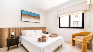 A modern bedroom with a bed, a nightstand, a chair, and a window with blinds. - Oroklini - Perfectly overlooking the pool (Oroklini)