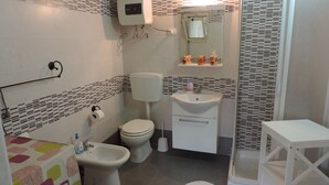 Bagno con toilette, bidet, lavandino e zona doccia.