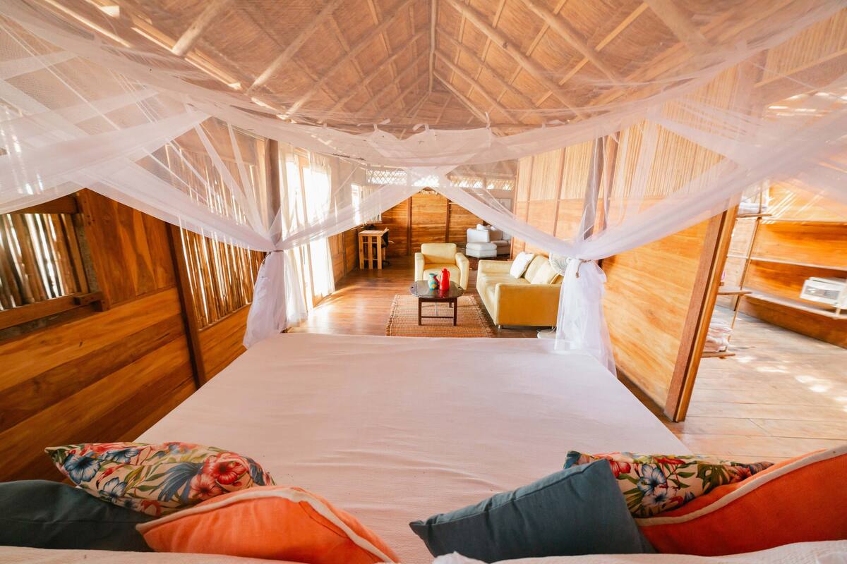 A room with a bed, a sofa, a small table, and a chair.