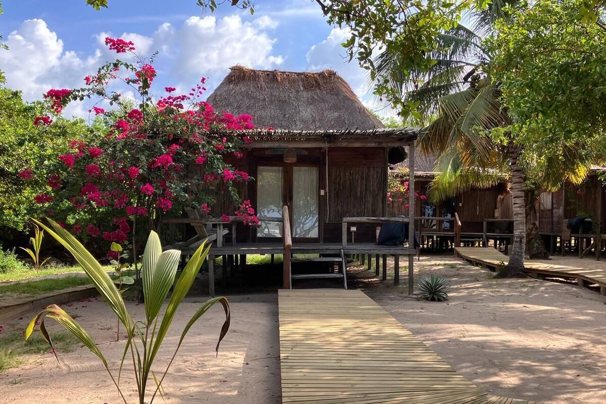 A rustic thatched-roof building with a wooden deck and outdoor seating area.