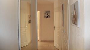 A hallway with white doors, a tiled floor, and a framed picture on the wall. - Bright apartment 87 m2 near Lake Annecy (Doussard)