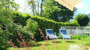 A garden with two lounge chairs, a wooden pergola, and a variety of plants. - Bright apartment 87 m2 near Lake Annecy (Doussard)