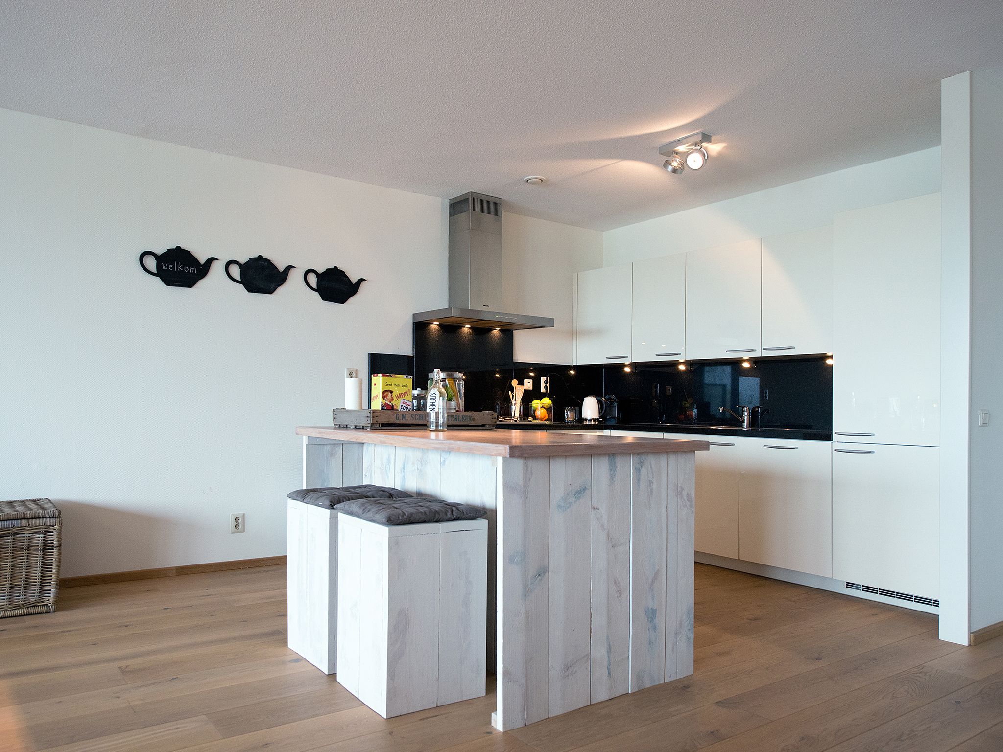 A modern kitchen with white cabinetry, a central island, and a black backsplash.