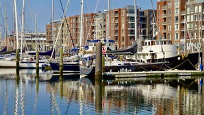A marina with multiple boats docked, surrounded by multi-story buildings. - BizStay Harbour Scheveningen Apartments (The Hague)