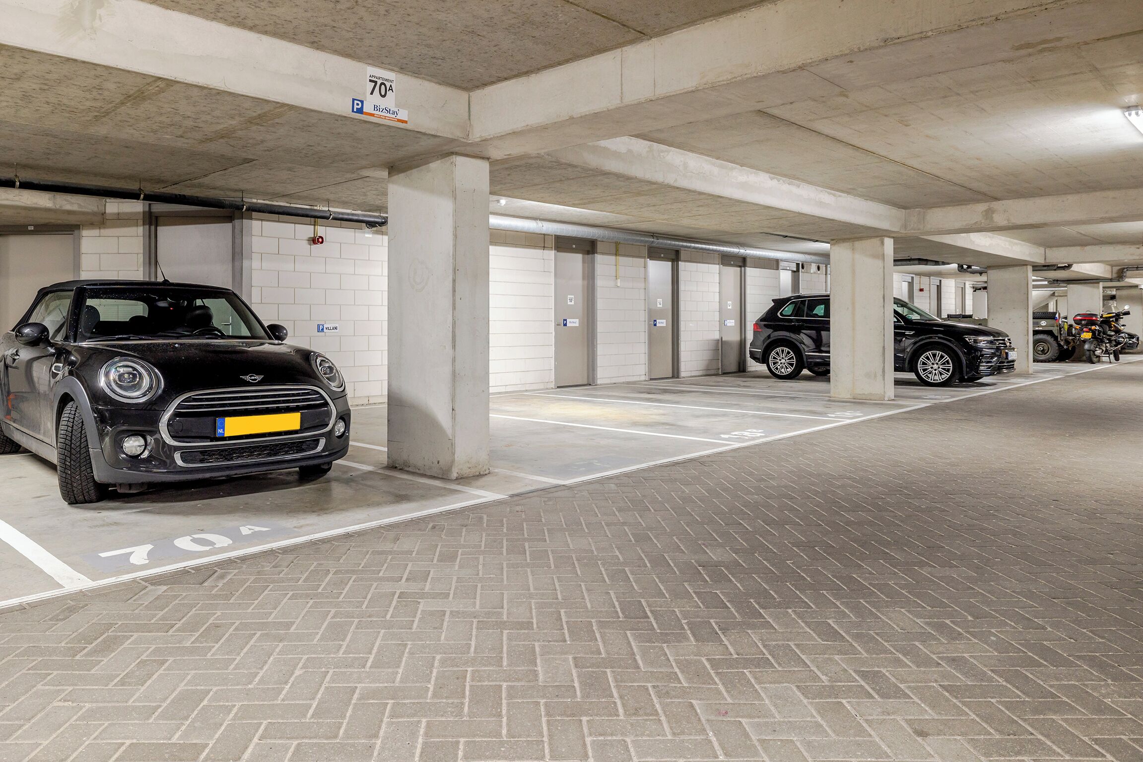 Un parking à plusieurs niveaux où sont garées plusieurs voitures.