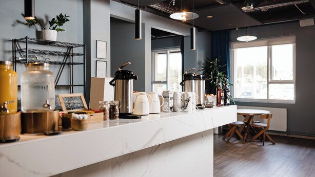 Una cocina moderna con encimera de mármol, cafeteras y una planta.