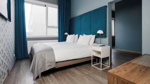 Una habitación de hotel moderna con una cama grande, un escritorio y una mesita de madera.