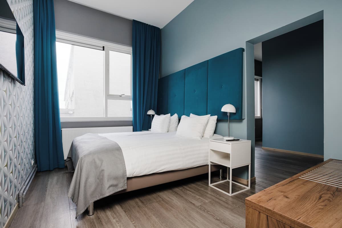 Una habitación de hotel moderna con una cama grande, un escritorio y una mesita de madera.