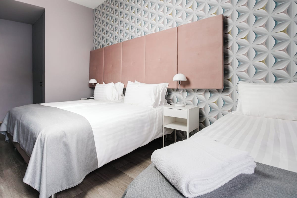 Una habitación de hotel moderna con una cama grande, una mesita de noche y un cabecero con diseño geométrico.