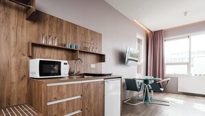 Una cocina moderna con armarios de madera, microondas y lavavajillas. Cuenta con una zona de comedor con mesa y sillas.