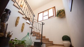 A staircase with a metal railing, potted plants, and decorative wall art.