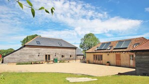 A rustic barn with a sloped roof and a small attached structure with skylights.