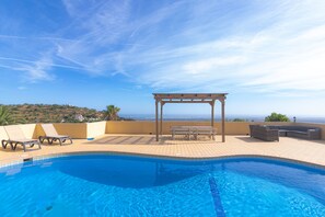 Une piscine dotée d’une pergola et d’un espace détente, offrant une vue sur le paysage côtier.