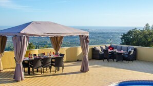 A terrace with a table and chairs, a sofa, and a canopy. - Villa Panoramica | 5 Bedrooms | Panoramic Views | Estói (Estoi)