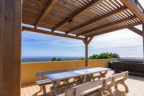 An outdoor patio with a wooden pergola, a tiled table, and a wicker sofa.