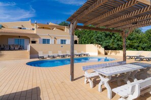 Ein Poolbereich mit Liegestühlen und einer Pergola.