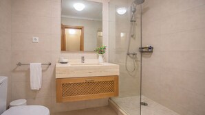 Een badkamer met toilet, wastafel, spiegel, douche en een kleine plant.