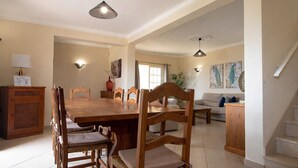 A spacious dining area with a wooden table and chairs, a sofa, and a staircase leading to an upper floor. - Villa Panoramica | 5 Bedrooms | Panoramic Views | Estói (Estoi)