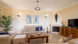 A living room with a sofa, a coffee table, a TV, and a fireplace. - Villa Panoramica | 5 Bedrooms | Panoramic Views | Estói (Estoi)