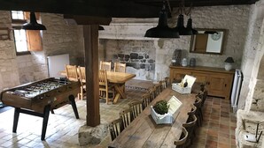 Un coin repas rustique avec une table en bois, des chaises et une table de baby-foot.