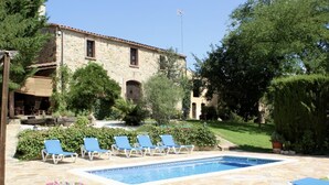 A pool area with lounge chairs, a stone building, and greenery. - Costabravapartment Can Marc with private pool and tennis court (Massanes (Girona))