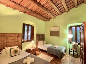 Une pièce avec deux lits, un plafond en bois, une fenêtre, une chaise et une lampe.
